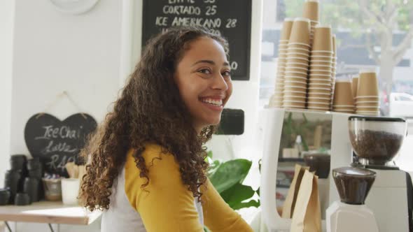 Portrait of happy biracial female client looking at camera and smiling at cafe