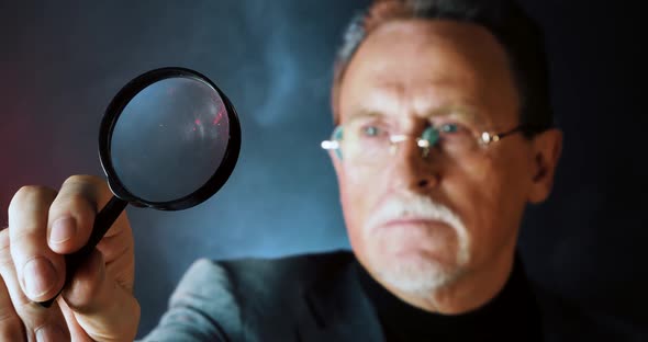 Enlarged Eye Of Mature Tax Inspector Looking Through Magnifying Glass