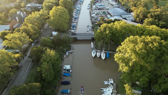 Aerial flying over port with boats and yachts docked in San Isidro city at golden hour