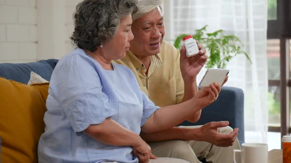 Asian senior couple having medical consultation video chat on mobile.