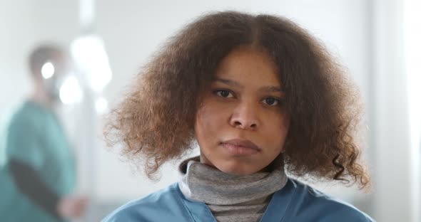 Portrait of Young Tired Afroamerican Female Doctor Looking at Camera in Hospital Corridor