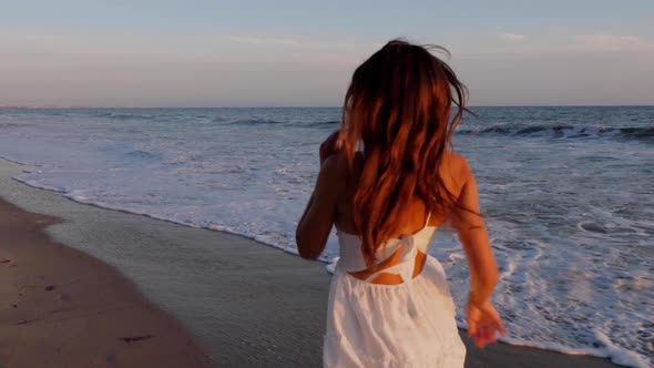 Beautiful woman in a white dress at the beach at sunset