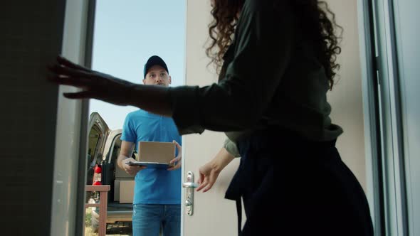 Slow Motion of Woman Opening Front Door Taking Parcel From Delivery Man Signing Paper