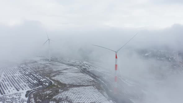 Wind turbine in a snowy landscape with early winter morning mist.