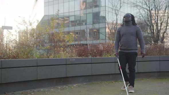 African American Blind Man with Stick Walking Alone on the City Street