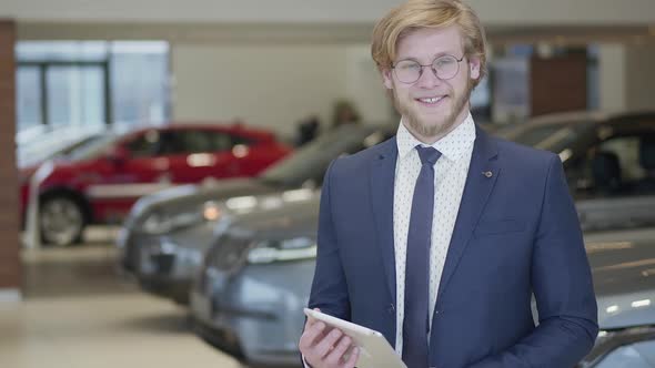 Portrait of a Successful Bearded Seller in Glasses Dressed in a Business Suit Standing in the Hall