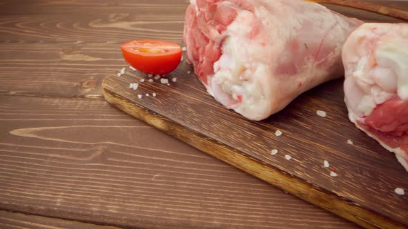 Two Raw Pork Drumsticks on Wooden Board Close Up