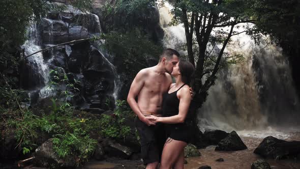 Couple Hugging and Kissing Under a Waterfall in a Cave