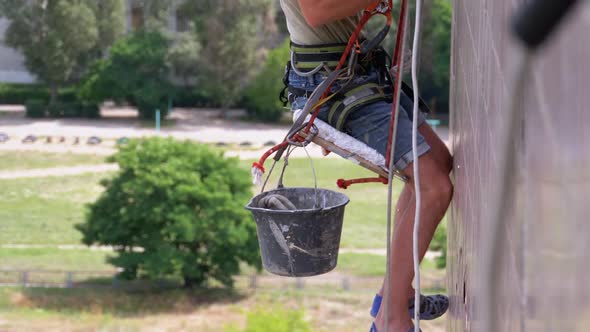 Industrial Climber in Equipment on Edge of Roof Prepares To Go Down on the Ropes