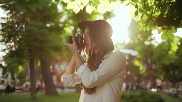 Young Beautiful Girl in Hat Photographing in City Park