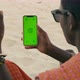 African Maasai Male Hand Holding a Smartphone with Green Screen and Swiping in the Front of Desert - VideoHive Item for Sale