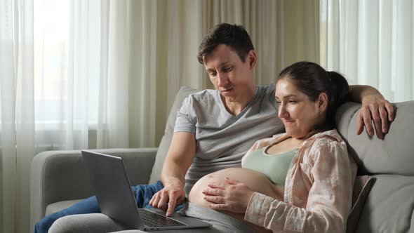 Husband and Wife Do Online Shopping for Future Baby Hugging