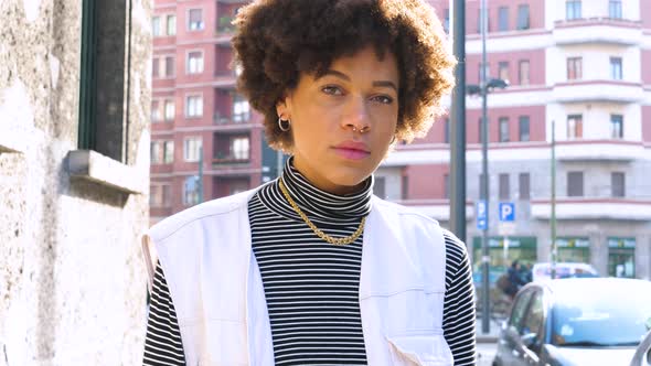 Slow motion portrait of young beautiful curly hair black woman outdoor in the city smiling healthy