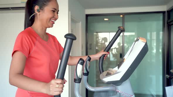 Woman working out on elliptical walking machine at gym.