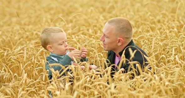 Portrait of a Young Father with His Son in a Wheat Field