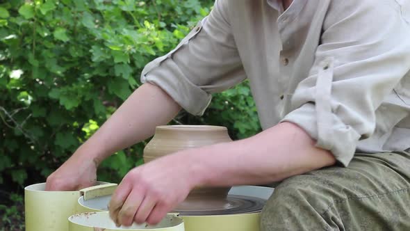 Male Potter of Caucasian Ethnicity Aligns a Clay Pot with a Wooden Tool Closeup