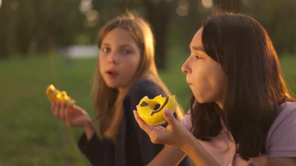 Side View Happy Teenage Girl Enjoying Taste of Doughnut in Slow Motion with Blurred Friend Eating