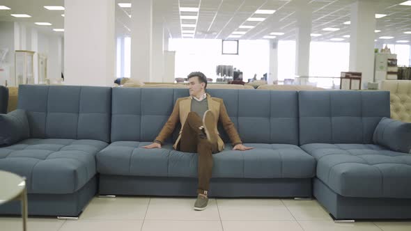 Man Sitting on Sofa at Furniture Store