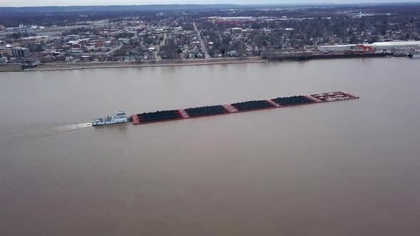 Aerial view of a tug boat pushing a barge filled with coal cruising on Louisville Kentucky Ohio rive