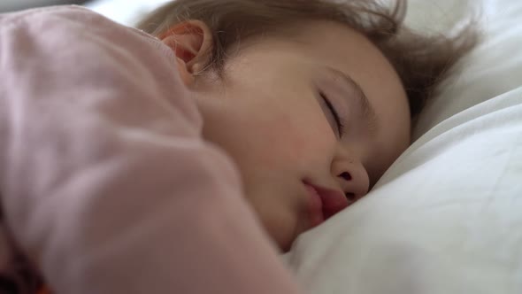 Authentic Cute Little Girl Sleeping Sweetly In Comfortable White and Grey Bed Close Up