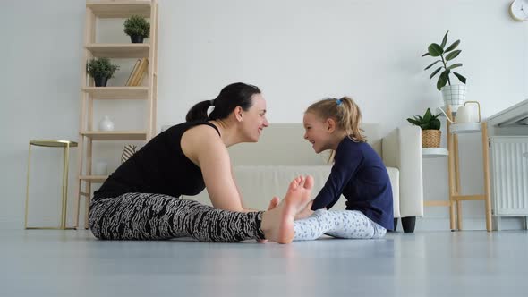 Woman with Daughter Doing Stretching on the Floor