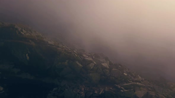 Flying next to a rocky cliff face through the clouds.