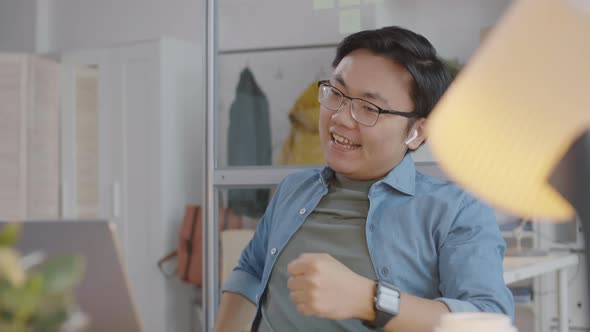 Positive Asian Man Celebrating Success during Office Workday