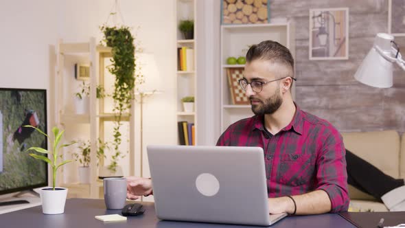 Freelancer Taking a Sip of Coffee While Working on Laptop