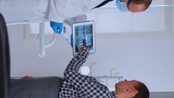 Dentist in Waiting Room Talking with Woman Patient About Xray