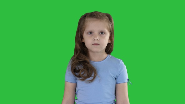 Little girl in jeans and blue t-shirt walking on a Green