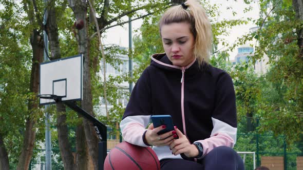 Blonde Girl in Tracksuit Sits Looks to Cellphone