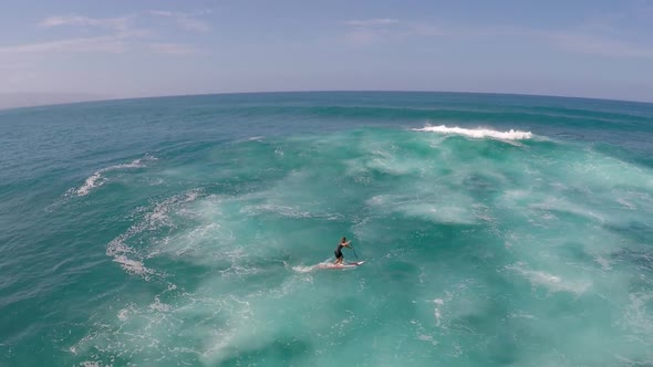 Aerial view of a man sup stand-up paddleboard surfing in Hawaii