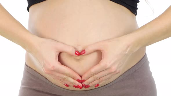 Pregnant Woman Holding Her Hands in a Heart Shape on Her Pregnant Belly, White, Closeup