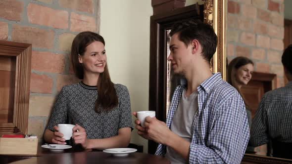 Couple In Cafe. Young People Drinking Coffee And Communicating