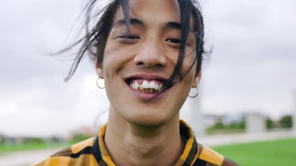 Happy Asian young man smiling on camera outdoor