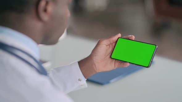 Rear View of African Doctor Holding Smartphone with Green Chroma Key Screen