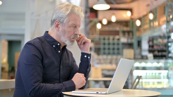 Pensive Old Man Using Laptop in Cafe