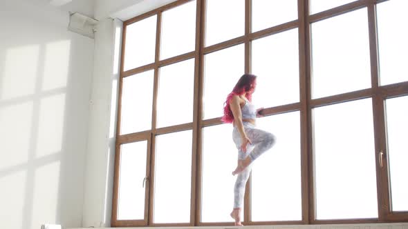 Concept of Stretching and Flexibility. Young Woman in Sportswear Doing Stretching Near Window in a