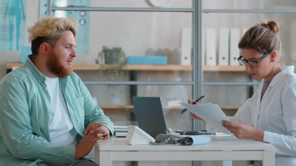 Overweight Man Talking with Female Doctor in Medical Office