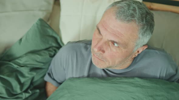 An Alarmed Man Suddenly Wakes Up In Bed Feeling Panic and Anxiety