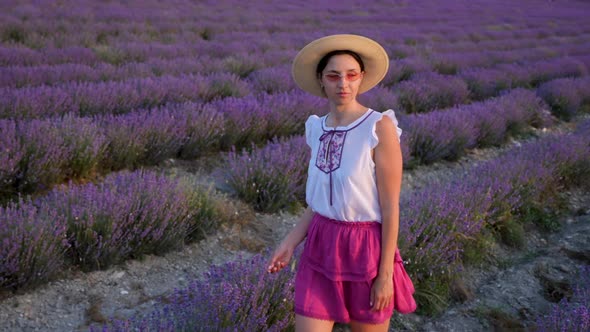 Woman in a Short Purple Dress and a Hat Stands on a Lavender Field