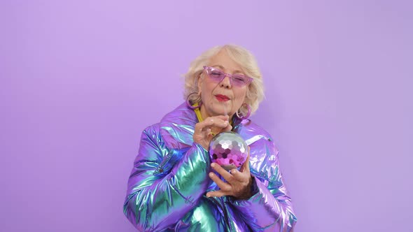 Charming Woman of Retirement Age Posing Standing on an Isolated Background Holding a Cocktail