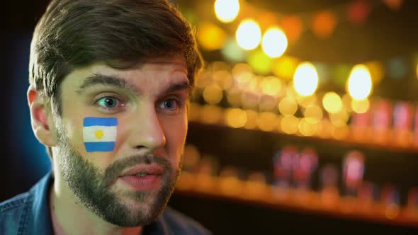 Argentinian Football Fan With Flag on Cheek Making Facepalm, Unhappy With Loss