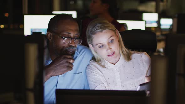 Professional businessman and businesswoman discussiong over digital tablet while sitting in modern o