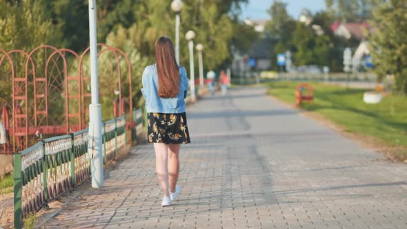 A Lonely Girl Walks Along the City's Promenade