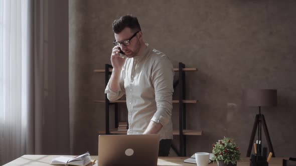 Handsome Businessman in Smart Casual and Eyeglasses Speaking on the Phone in Office