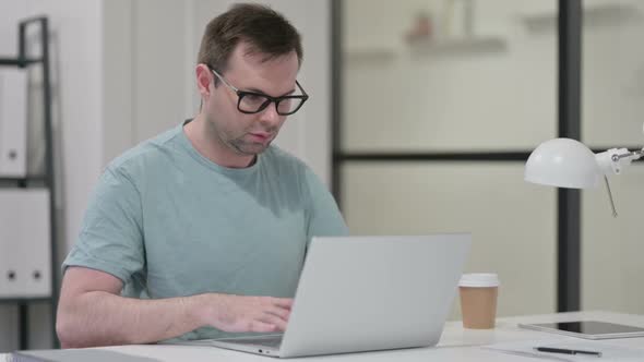 Young Man Working on Laptop in Office