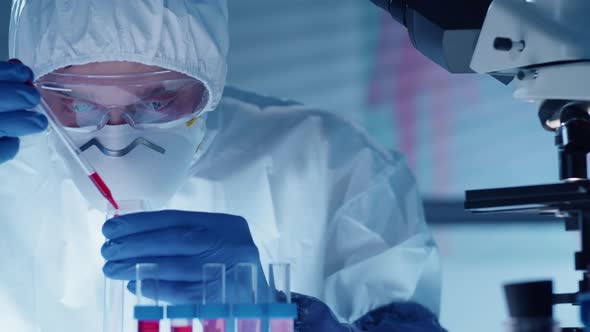 Male Scientist in Protective Uniform Pouring Blood into Test Tube