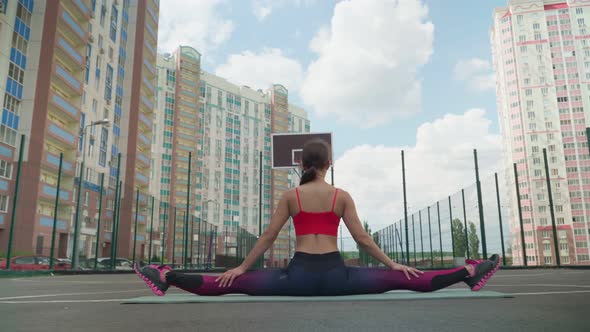 Stretching and flexibility. Young athletic girl in sports clothes, sits in splits