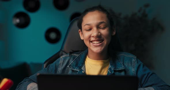 Closeup of Girl's Hands Taking Notes with Pencil in Notebook Laptop Headphones Teenage Girl Has